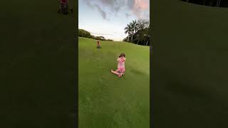 Girl rides scooter down grass hill then falls and boy on kiddie tricycle crashes into her