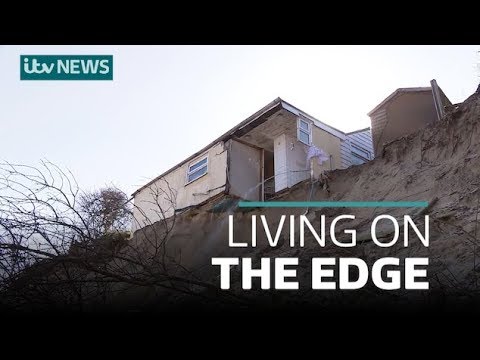 Several damaged homes dangle precariously along washed out ...