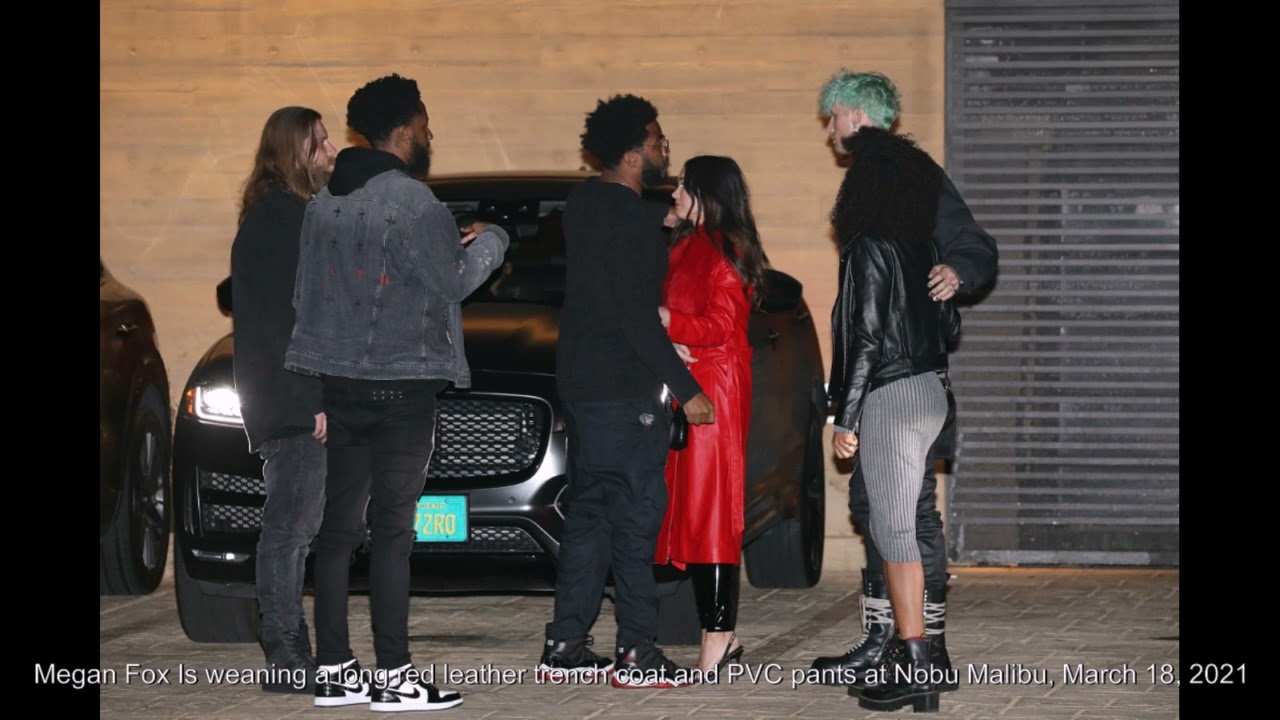 Megan Fox Is weaning a long red leather trench coat and PVC pants at