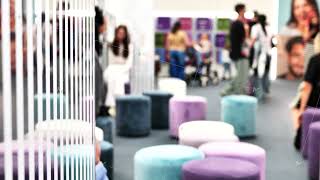 Exhibition guests interacting in a contemporary event space with soft velvet seating screenshot 3