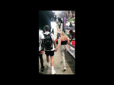 Girl holds hands with random guys at boardwalk