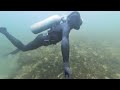 Spectre frogman diving using vintage scuba gear wearing a latex rubber drysuit