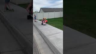 Little girl rides toy walker car on grass and falls over