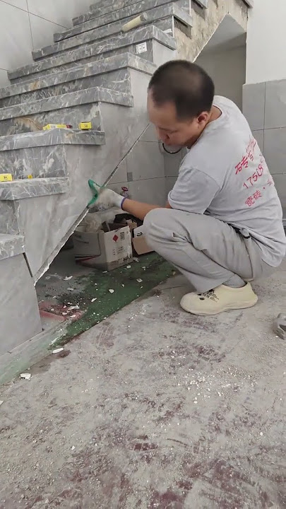 A worker breaks tiles for a staircase