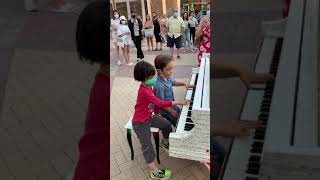 Two amazing talented 6-year-old kids playing duet on a public street piano