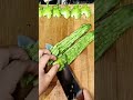 cutting a long green bitter melon into several small pieces using a sharp kitchen knife on a board