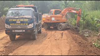 Excavators and cars are carrying soil to fill the road