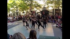 A large dance troupe performing on the street.