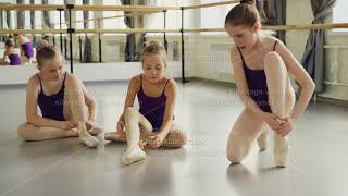 Three cute girls are trying to put on ballet slippers sitting on studio floor together and chatting screenshot 2