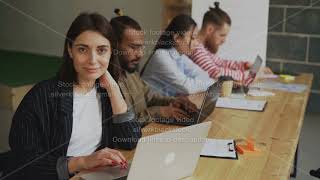 Portrait of smiling female freelancer looking at camera sitting with laptop computer at busy