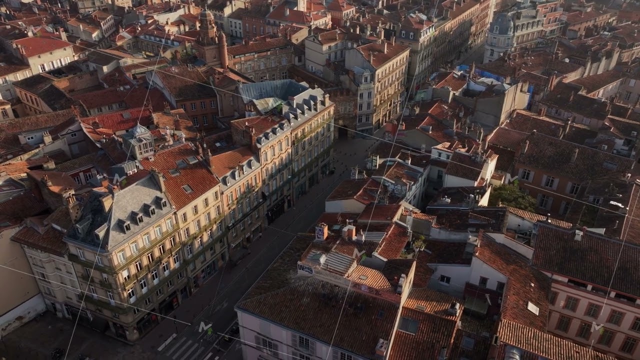Aerial view revealing Toulouse historic center, terracotta rooftops gleaming under golden morning
