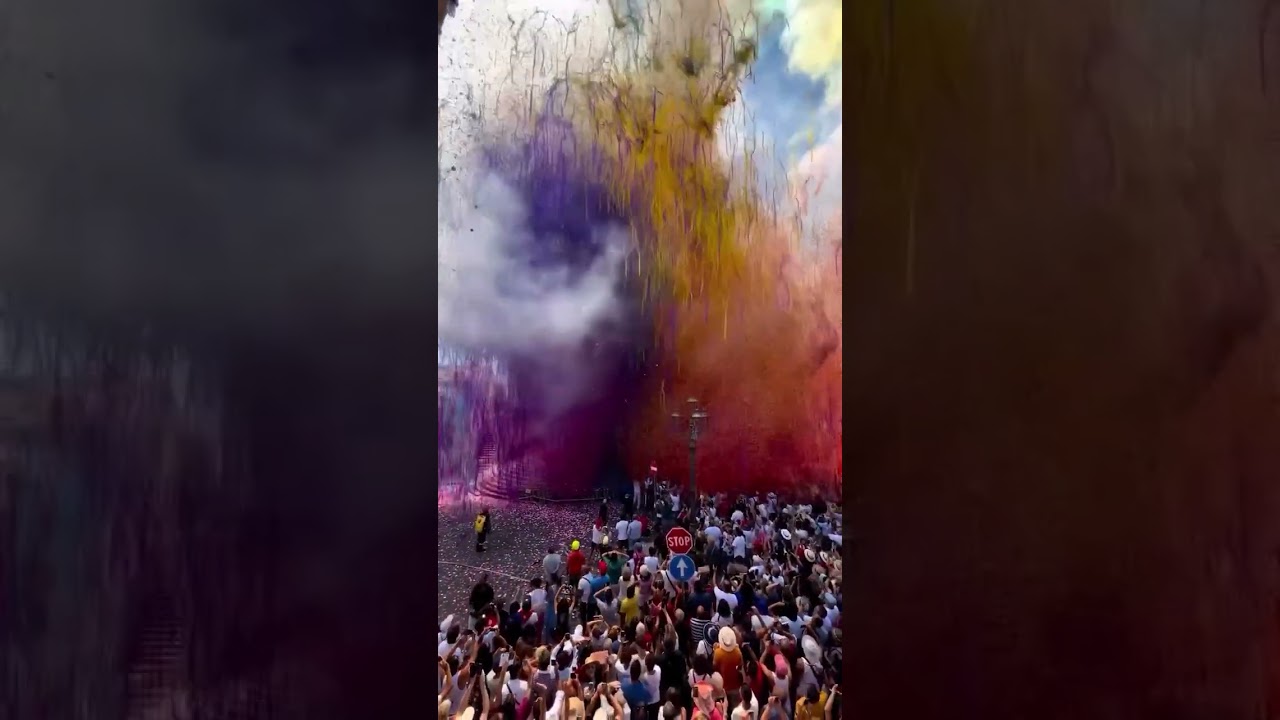 A vibrant festival scene unfolds as colorful smoke&confetti burst into the sky outside  grand church