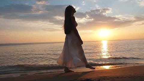 Woman in sundress walking on the beach at sunset - Royalty Free by YOUR STOCK FOOTAGE