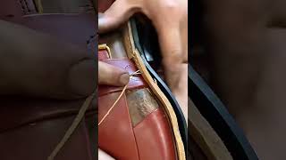 Artisan traditional shoemaker hand stitching durable leather sandals with yellow thread