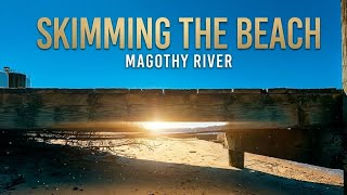 Through a gap, skimming the beach flying under a pier on the Magothy River in Annapolis, MD