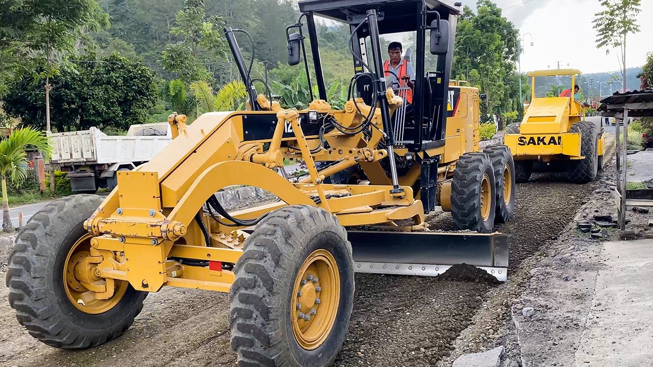 CAT 120K Grader and SAKAI Soil Compactor Working Together in Public to Construct Road - Paya Tumpi