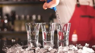 Close-up Bartender Pouring Some Drink From Bottle Into Shot Glasses on Wooden Counter | Stock screenshot 3