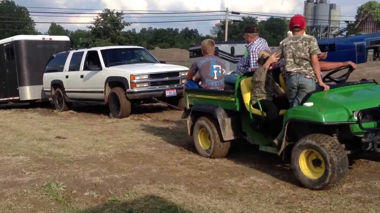 John Deere Gator pulling out a stuck suburban with trailer.