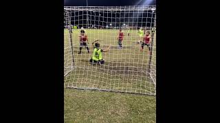 Boy playing goalkeeper makes a save by blocking soccer ball with his head