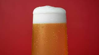 Mug of Fresh Light Beer with White Foam in Red Background Air Bubbles Moving in Glass Slow Motion