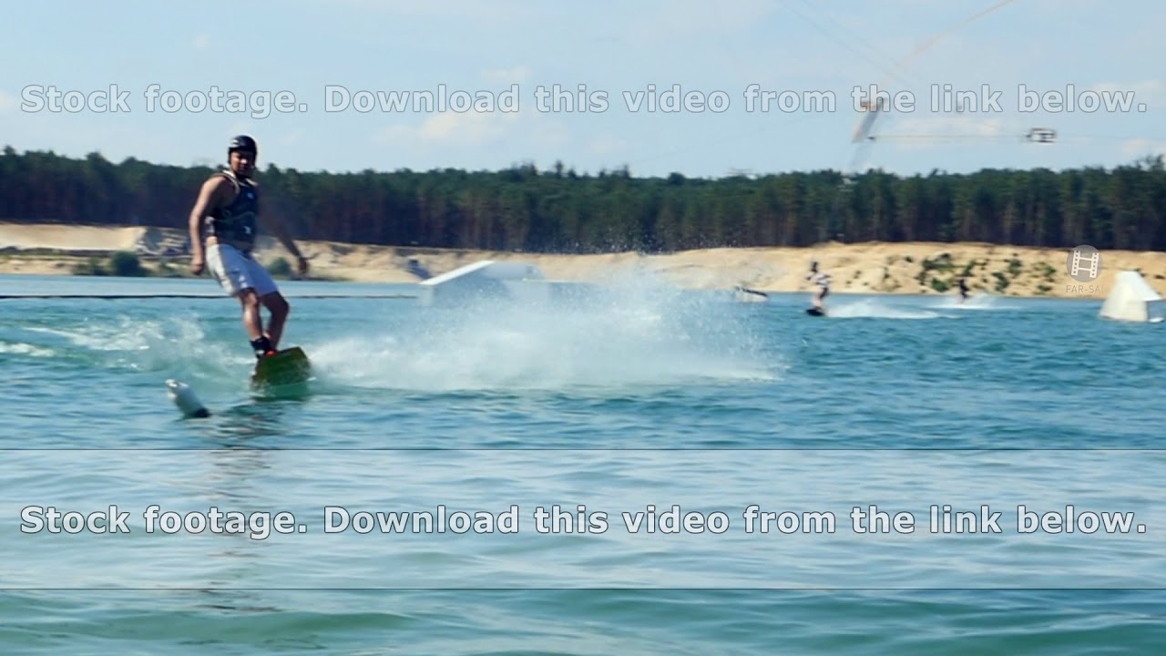 Young man Riding Wakeboard On Lake Park. Moving into camera and crash into water