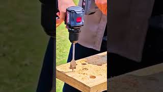 drilling multiple large holes into a wooden board using a powerful cordless drill and flat spade bit