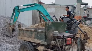 Excavator scooping stones onto three-wheeled farm workers