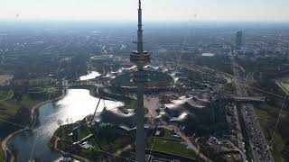 High altitude flight over Munich Olympiapark showcasing Olympiaturm television tower, iconic stadium