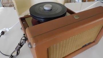 RCA 6EY-3-A portable 45 RPM record player playing  a stack of records.
