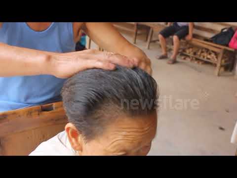Chinese barber practising the rare art of cutting hair with hot tongs