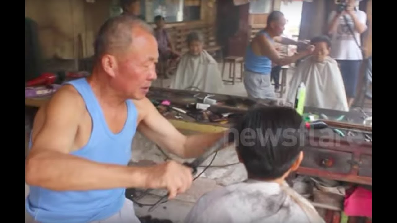 Chinese barber practising the rare art of cutting hair with hot tongs