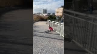 Boy on skateboard ollies stairs on boardwalk then crashes into fence