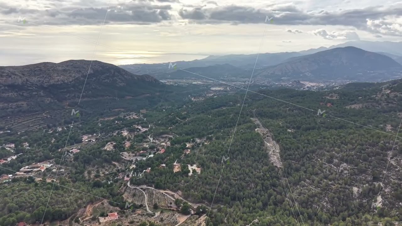 Tranquil sunset valley captured from above showcasing mountain paths and shimmering ocean backdrop