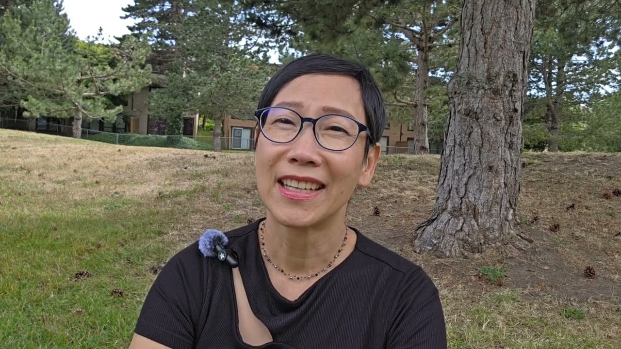 Woman sitting outside in a park with trees behind