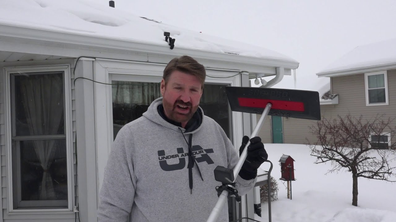 Photovoltaic panels on the roof with snow, with a snow shovel in