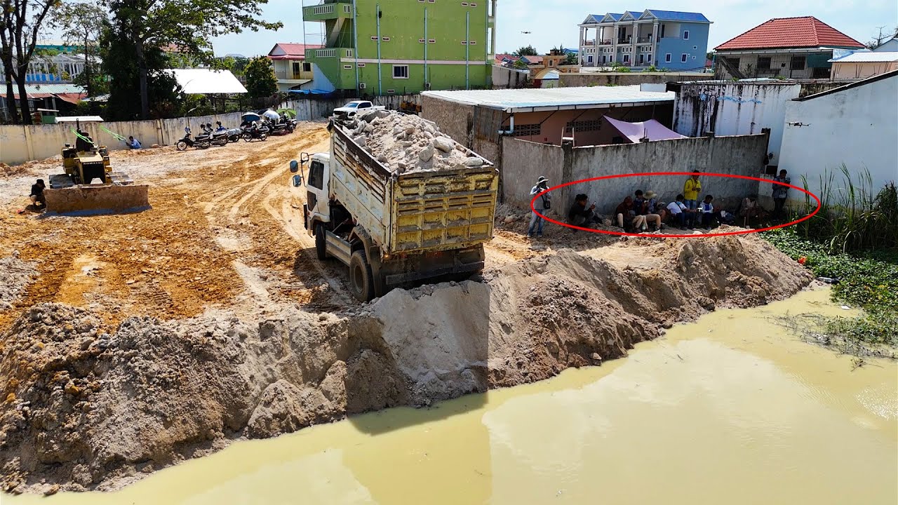 Great filling activity with bulldozer and dump trucks pushing soil 