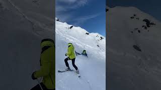 Group of people ski down mountain then multiple kids fall and slide down slope