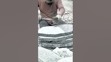 Skilled worker grinding stacked stone slabs into smooth, even surfaces for precise shaping