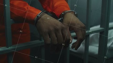 Hands in handcuffs leaning on prison cell bars