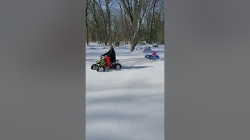 Polaris 110 towing kid on tube in snow