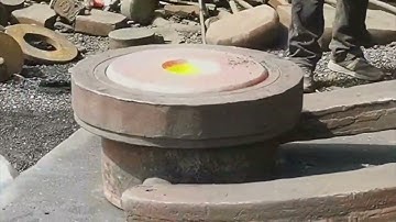 Forging high-temperature rectangular iron blocks into circular iron cakes before drilling