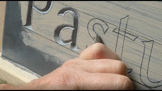 Stone carver carving lettering on slate