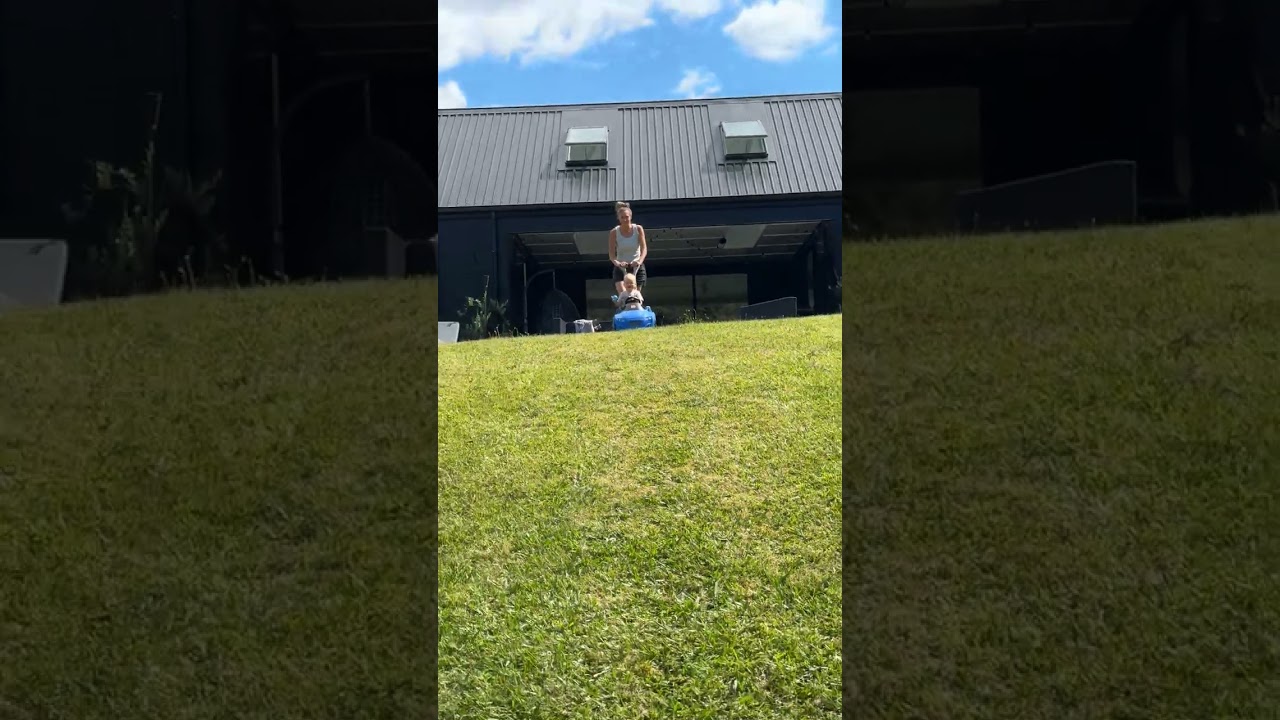 Mom pushes baby boy down grass hill in blue car and crashes into dog