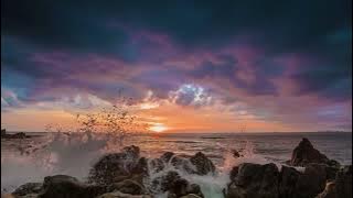 Dramatic sunset on a tropical beach with rocky shoreline in 4K