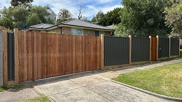Colorbond fence with exposed posts and vertical merbau cladded gates