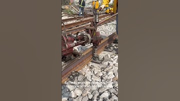 Railway workers push machines to screw on the railway