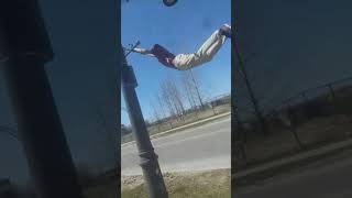 Guy hangs from light pole, falls, and lands awkwardly