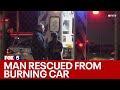 Firefighter rescues man trapped in burning car