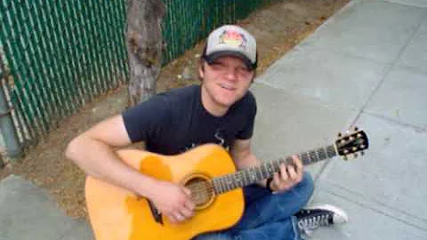 Ben Kasica playing guitar on the sidewalk