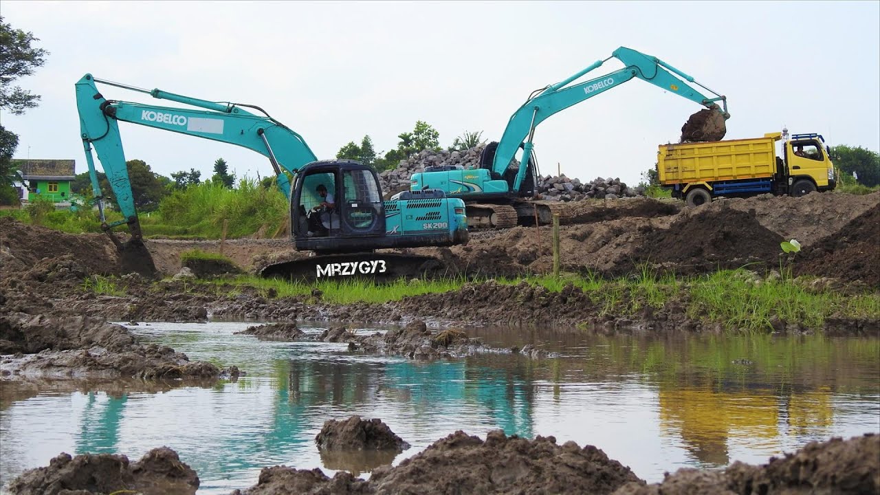 Kobelco SK200 Excavator And Trucks Digging Dirt For The Retention Pond ...